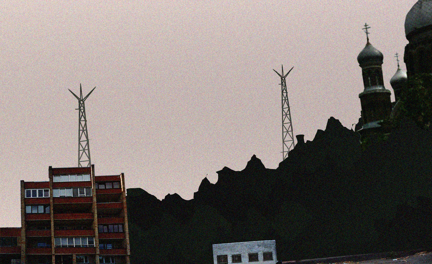 a series of radio towers and buildings with a setting sun