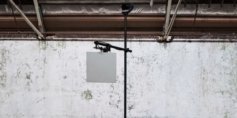 a square speaker on a tall black pole, with a circular speaker at the top in a distressed venue